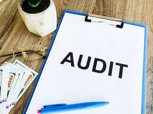 Clipboard with text audit on wood desk.
