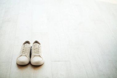 Ahşap zemin üzerinde yeni şık beyaz spor ayakkabı çifti.