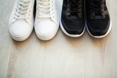 Ahşap zemin üzerinde yeni şık beyaz spor ayakkabı çifti.