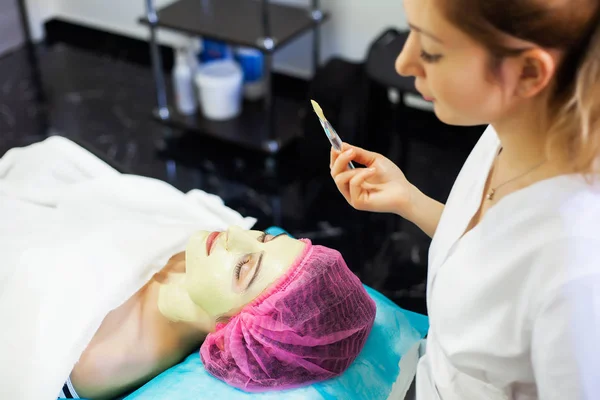 Spa therapie voor jonge vrouw gezichtsmasker gelet op de salon van de schoonheid. — Stockfoto