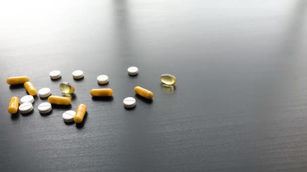 Медицинские таблетки. Цветные таблетки и капсула на черном столе. Тема аптеки, капсульные таблетки с лекарственными антибиотиками в упаковках — стоковое видео