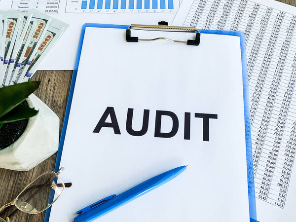Clipboard with text audit on wood desk.