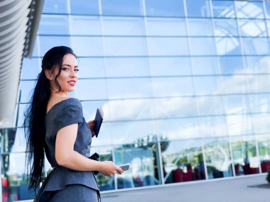 Tatil. Gülümseyen kadın yolcu havaalanı yolcu salonundan bavulçekerek kapıdan çıkışa doğru ilerliyor