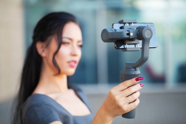 Blogger girl shoots a video about traveling on an electronic stabilizer. clipart