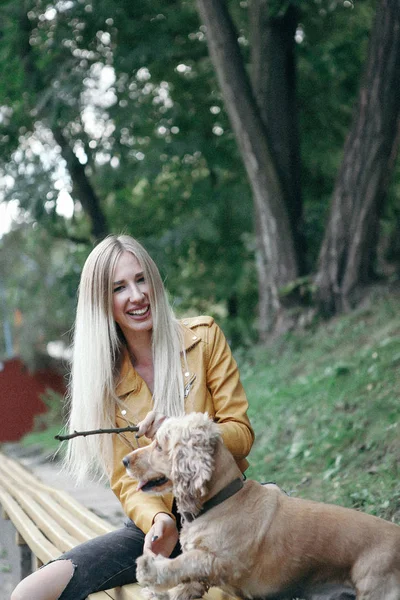 Gadis muda dengan anjing berjalan di taman dan menikmati hari musim panas yang indah . — Stok Foto