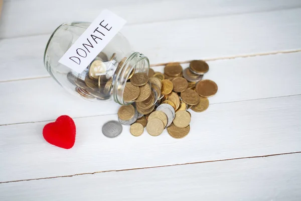 Spenden Sie! Glas mit Geld auf weißem Holz Hintergrund — Stockfoto