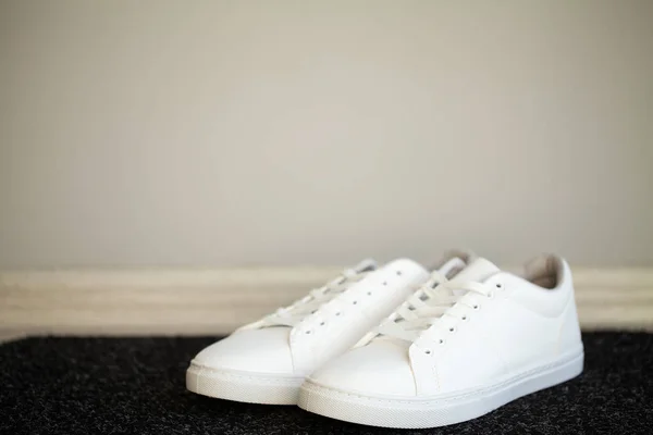 Dvojice nových stylových bílých tenisky na podlaze doma — Stock fotografie