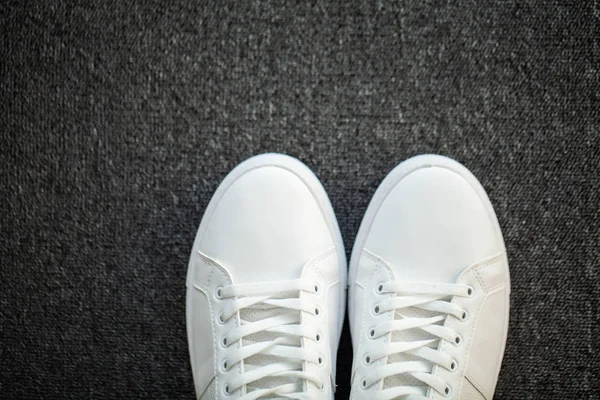 Par de nuevas zapatillas blancas con estilo en el suelo en casa —  Fotos de Stock