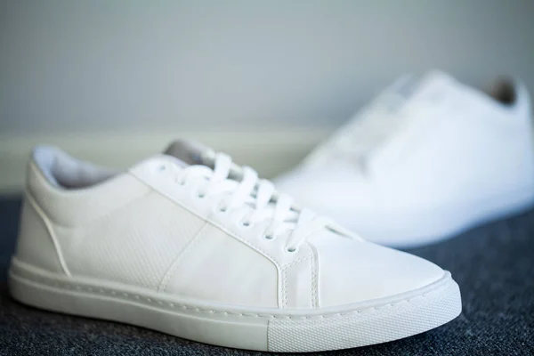 Пара новых стильных белых кроссовок на полу дома — стоковое фото