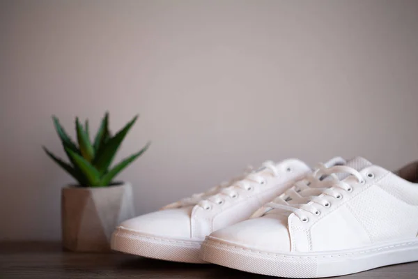 Par de nuevas zapatillas blancas con estilo en el suelo en casa —  Fotos de Stock