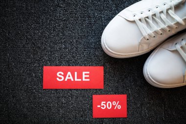 Gri arka planda indirimli yeni şık beyaz spor ayakkabı çifti.