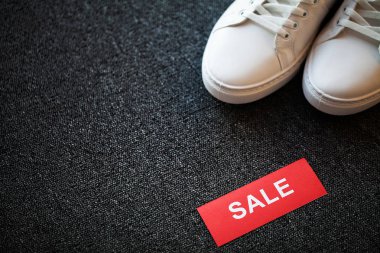 Gri arka planda indirimli yeni şık beyaz spor ayakkabı çifti.