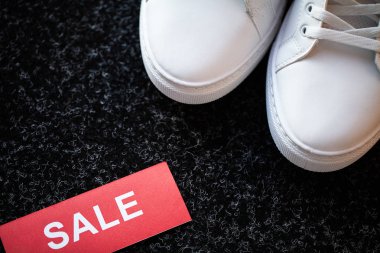 Gri arka planda indirimli yeni şık beyaz spor ayakkabı çifti.