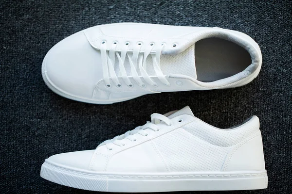 Pair of new stylish white sneakers on floor at home — Stock Photo, Image