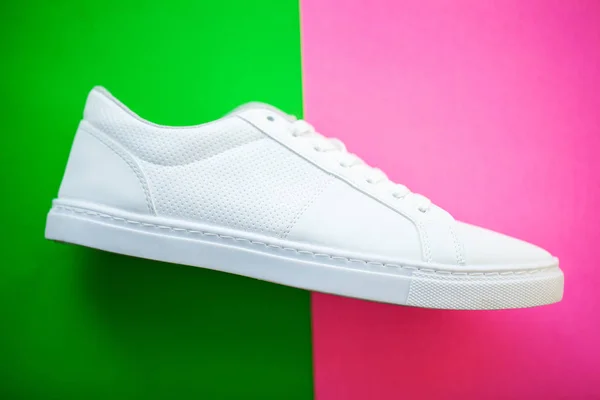 Nové stylové bílé tenisky na zelené růžové pozadí. — Stock fotografie