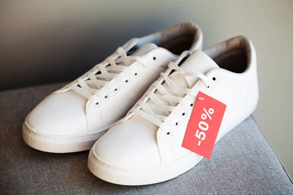 Par nya snygga vita sneakers med rabatt på grå bakgrund. — Stockfoto