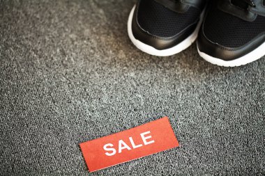 Gri arka planda indirimli yeni şık siyah spor ayakkabı çifti.