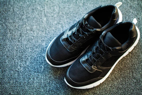 Пара новых стильных черных кроссовок на полу дома — стоковое фото