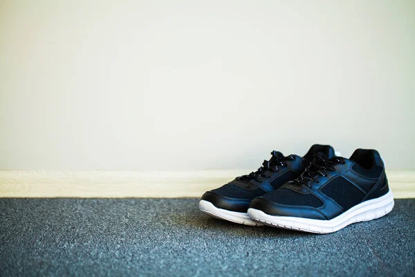 Pair of new stylish black sneakers on floor at home — Stock Photo, Image