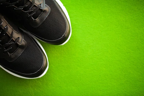 Пара новых стильных кроссовок на зеленом фоне . — стоковое фото