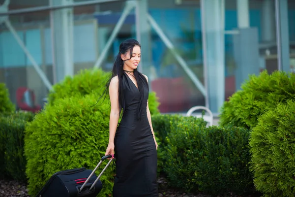 휴가. 공항 중앙홀을 통해 가방을 당기는 출구로 가는 미소 짓는 여성 승객 — 스톡 사진