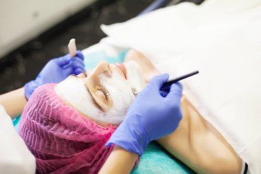 yüz maskesi Güzellik Salonu sahip genç bir kadın için spa terapisi.