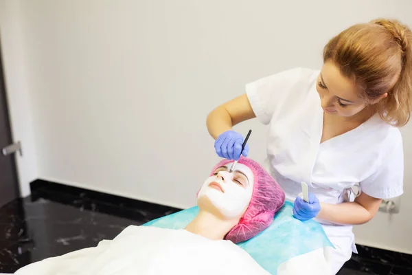 Spa therapie voor jonge vrouw gezichtsmasker gelet op de salon van de schoonheid. — Stockfoto