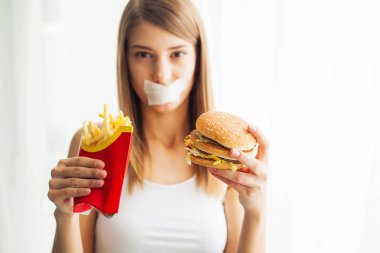 Diyet. Kadın portre bir Burger ama sıkışmış skochem ağız, diyet, abur cubur, irade beslenme kavramı yemek istiyor