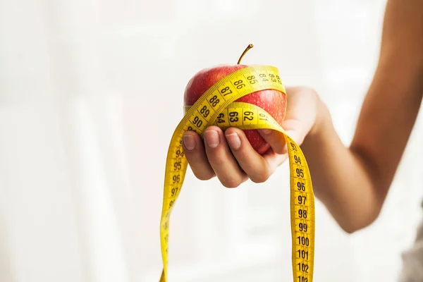 Conceito de dieta. Maçã com fita métrica na mão feminina — Fotografia de Stock