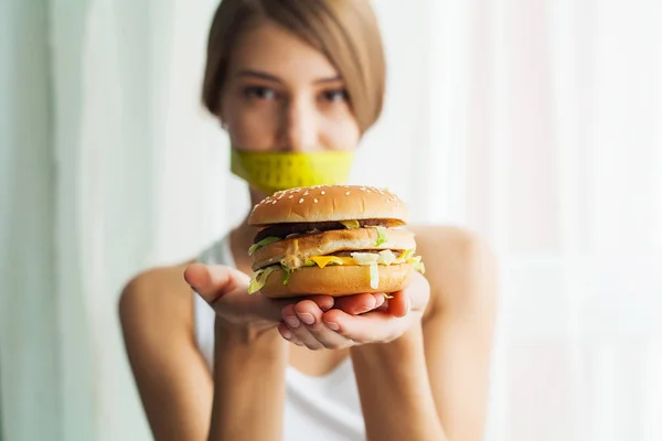 Dieta. Retrato mujer quiere comer una hamburguesa pero pegado skochem boca, el concepto de dieta, comida chatarra, fuerza de voluntad en la nutrición — Foto de Stock