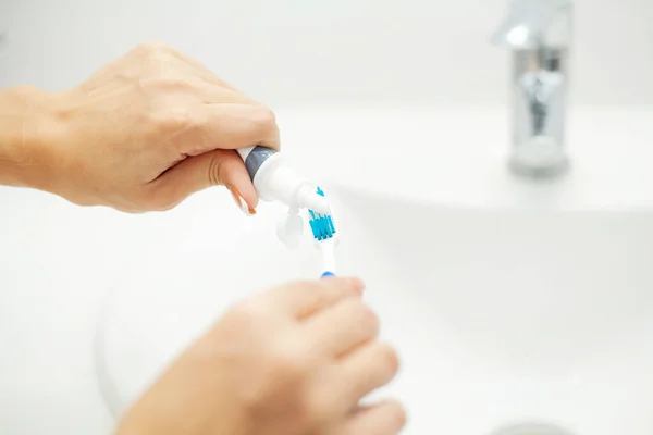 Close Up hands woman press toothpaste onto toothbrush