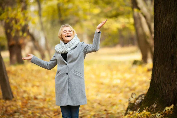 Erkältung und Grippe. junge Frau im grauen Mantel spaziert durch den Herbstpark — Stockfoto