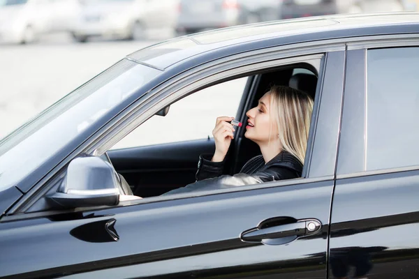 Mulher usar batom dentro de seu carro novo — Fotografia de Stock