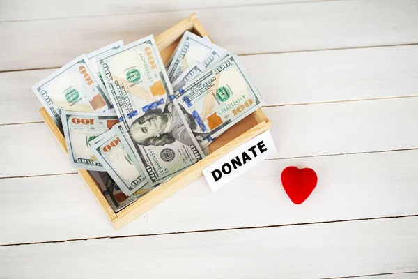 Box with money on white wood background. Donate conception — Stock Photo, Image