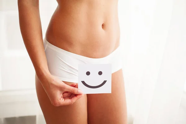 Salud de las mujeres. Primer plano de la hembra sana con hermoso ajuste cuerpo delgado en bragas negras sosteniendo tarjeta verde con la cara sonriente feliz en las manos — Foto de Stock