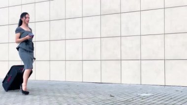 Tatil. Gülümseyen kadın yolcu havaalanı yolcu salonundan bavulçekerek kapıdan çıkışa doğru ilerliyor