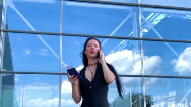 Seyahat. İş Kadını havaalanında konuşurken akıllı telefon dan el bagajı ile yürürken havaalanına kapı gidiyor.