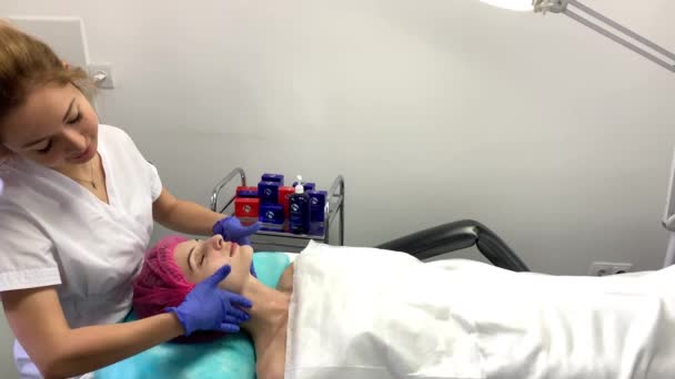 Wellnesstherapie für junge Frau mit Gesichtsmaske im Schönheitssalon. — Stockvideo