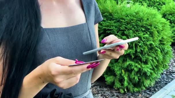 Mulher às compras com cartão de crédito. Menina bonita com cartão de ouro usando telefone — Vídeo de Stock