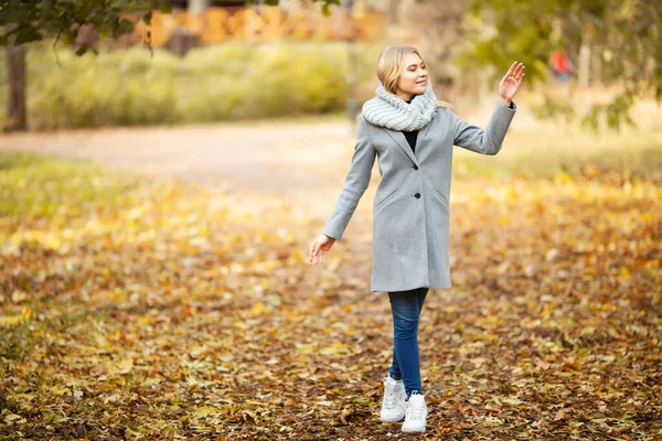 Холод і грип. Молода жінка в сірому пальто, що йде в осінньому парку — стокове фото