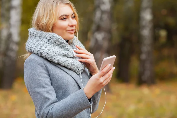 Young Beauty woman listening music in autumn forest