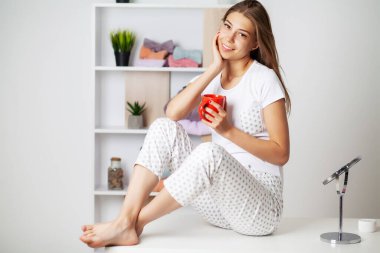 Yeni pijamalarıyla gülümseyen güzel bir kadın yatmaya hazırlanıyor.