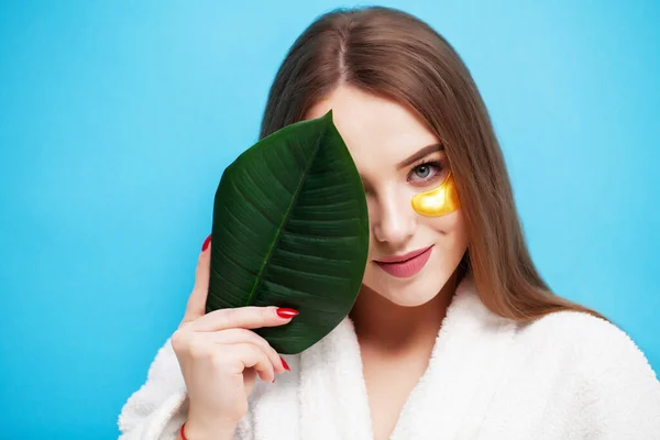 顔のケア顔の健康の近くに緑の葉を保持する若い女性 — ストック写真