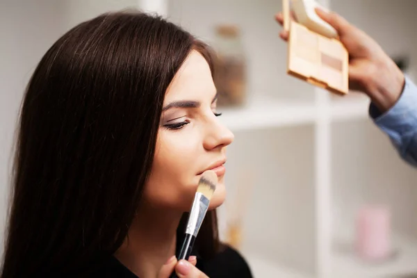 Profesjonalny wizażysta robi makijaż wieczorowy młodej kobiecie — Zdjęcie stockowe