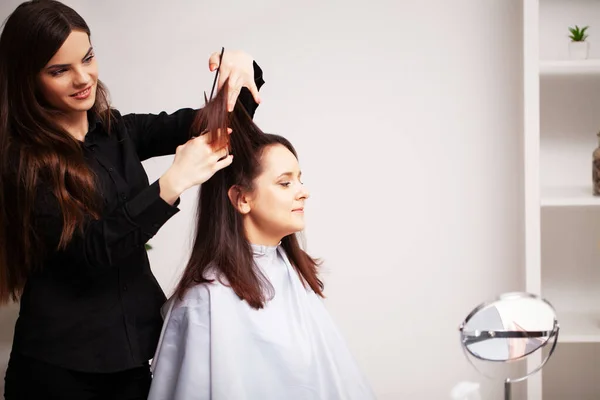 Stilista professionista rende una giovane donna una bella acconciatura — Foto Stock