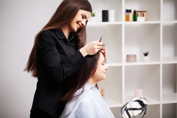 Stilista professionista rende una giovane donna una bella acconciatura — Foto Stock