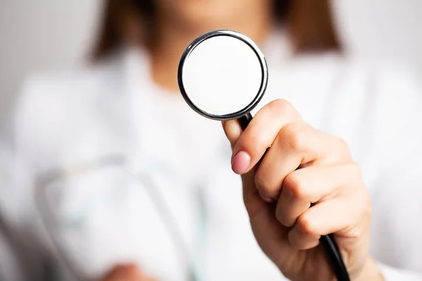 Médico mulher segurando estetoscópio em mãos de perto — Fotografia de Stock