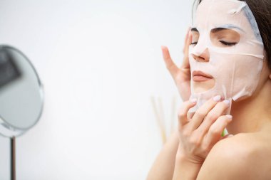 Bir kadın cildine dikkat etmek için nemlendirici bir maske kullanır.