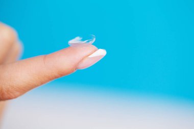 Parmağında göz merceği tutan bir kadın.