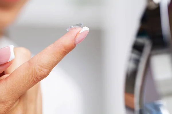 Mujer sosteniendo una lente de contacto para el ojo en su dedo — Foto de Stock